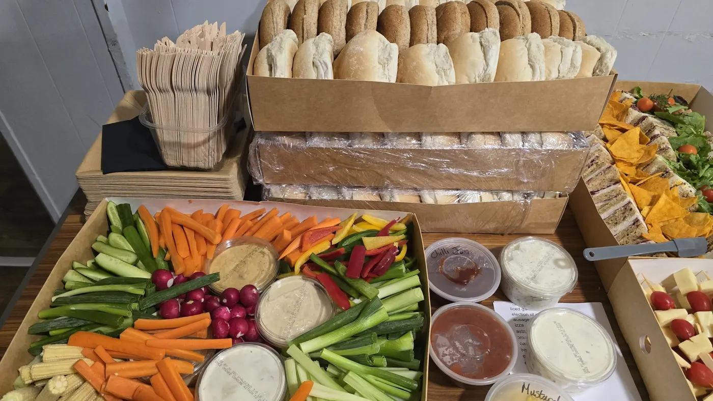A buffet spread of sandwiches, crudités, dips, and bread rolls ready for an event.
