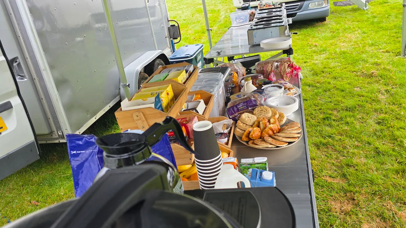 Outdoor catering setup with food and drinks laid out on a table.
