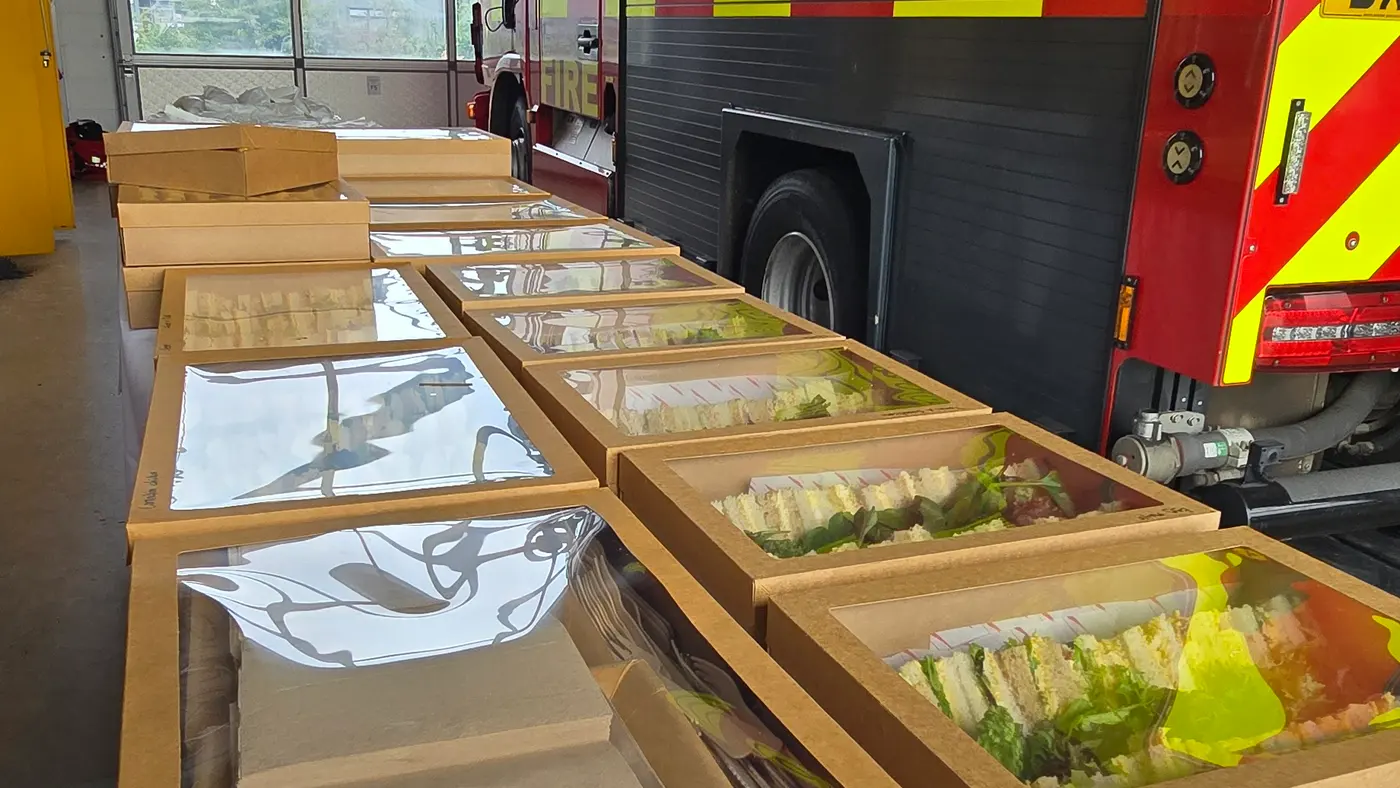 Catering boxes of sandwiches are laid out in front of a fire engine.