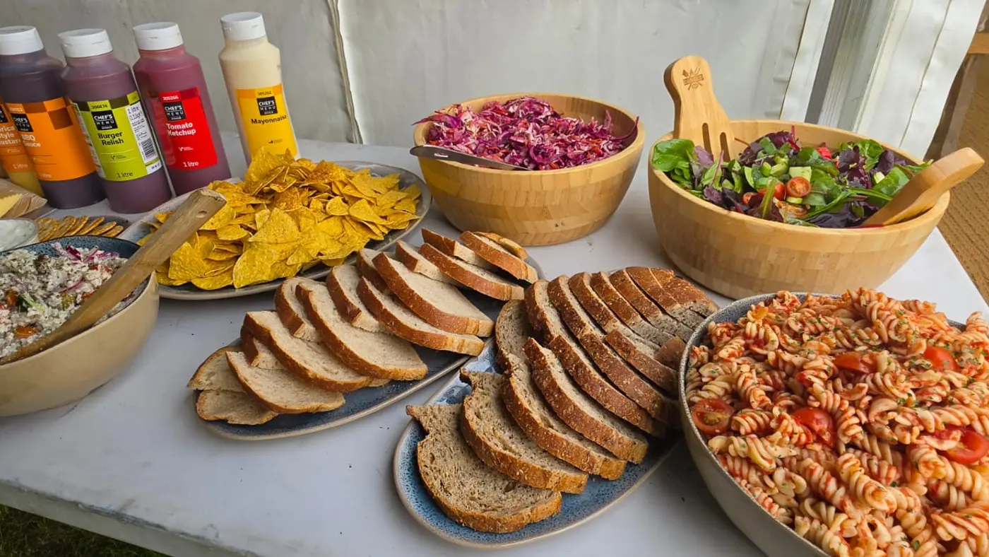 A buffet spread with salads, bread, chips, and sauces laid out on a table.