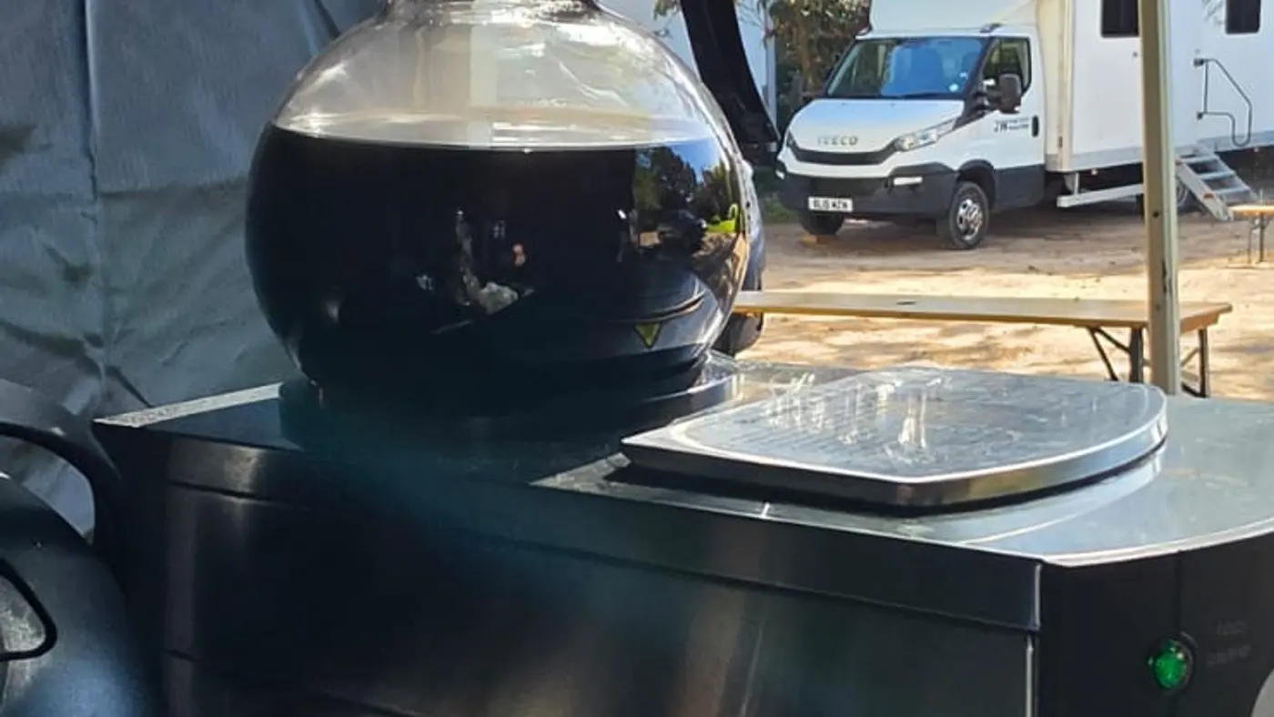 Steaming coffee pot sits on a catering unit with a film set in background.