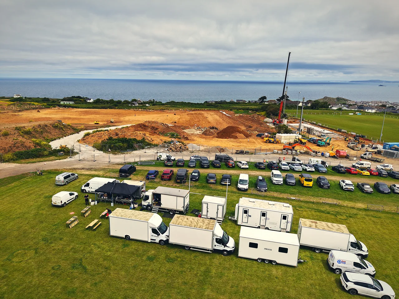 Salt Wind Catering's film unit base lined up on location in Cornwall — mobile kitchen, gazebos and crew dining set up beside the production's vehicles.
