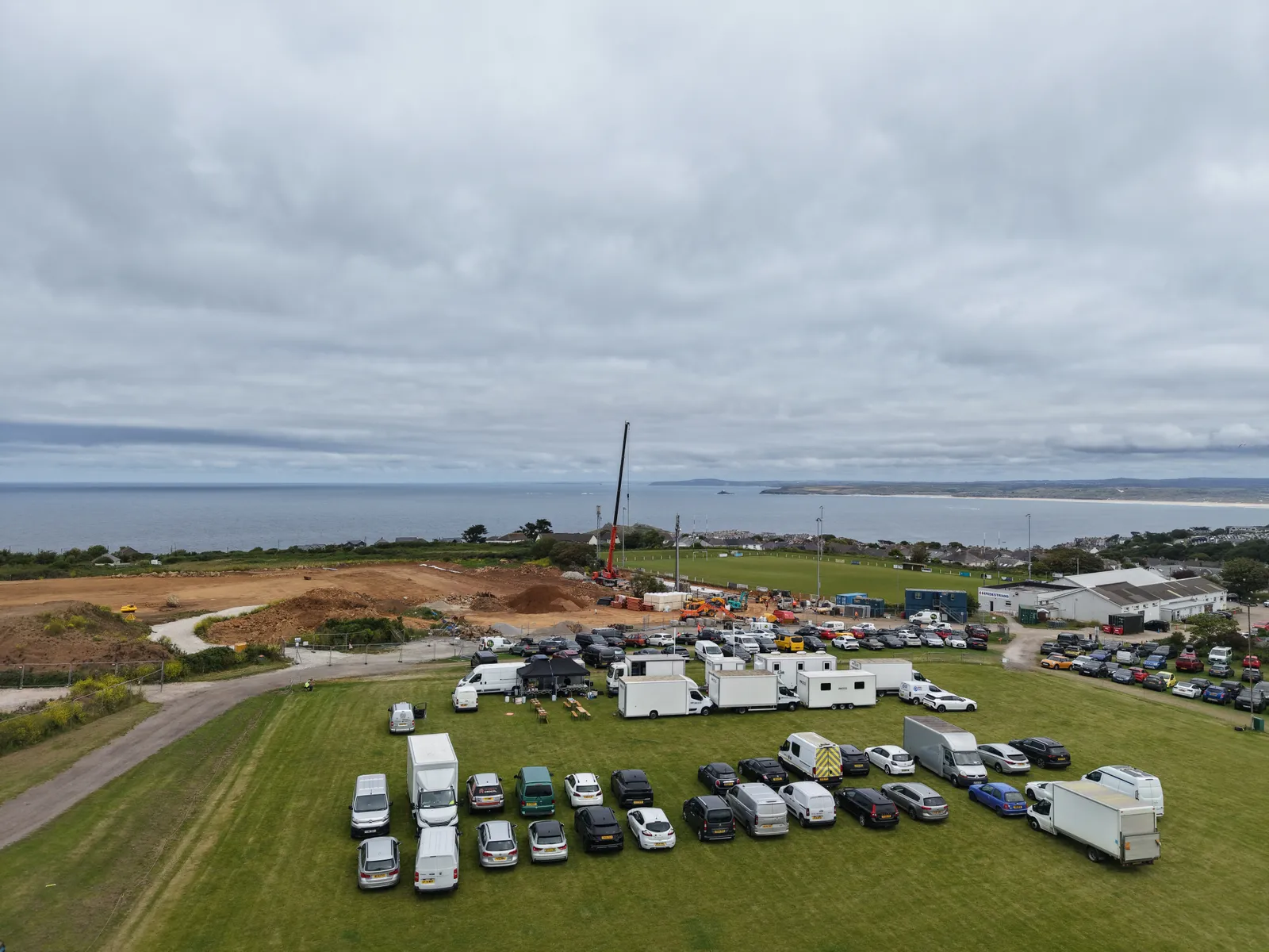 Aerial view of a film unit base on the Cornish coast — catering gazebo, crew dining and facilities units laid out on the field