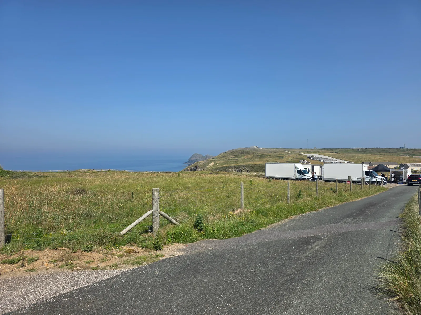 Production unit trucks parked along a Cornish coast road above the sea, catered on location by Salt Wind Catering