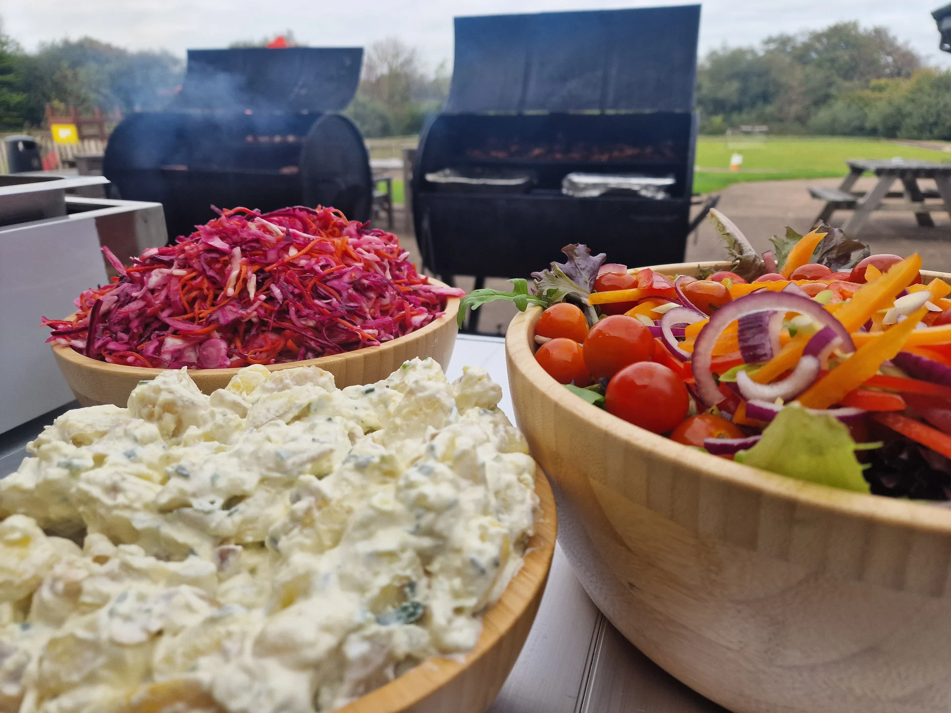 Salt Wind Catering — charcoal BBQ smokers with fresh salad bowls at a Cornwall event